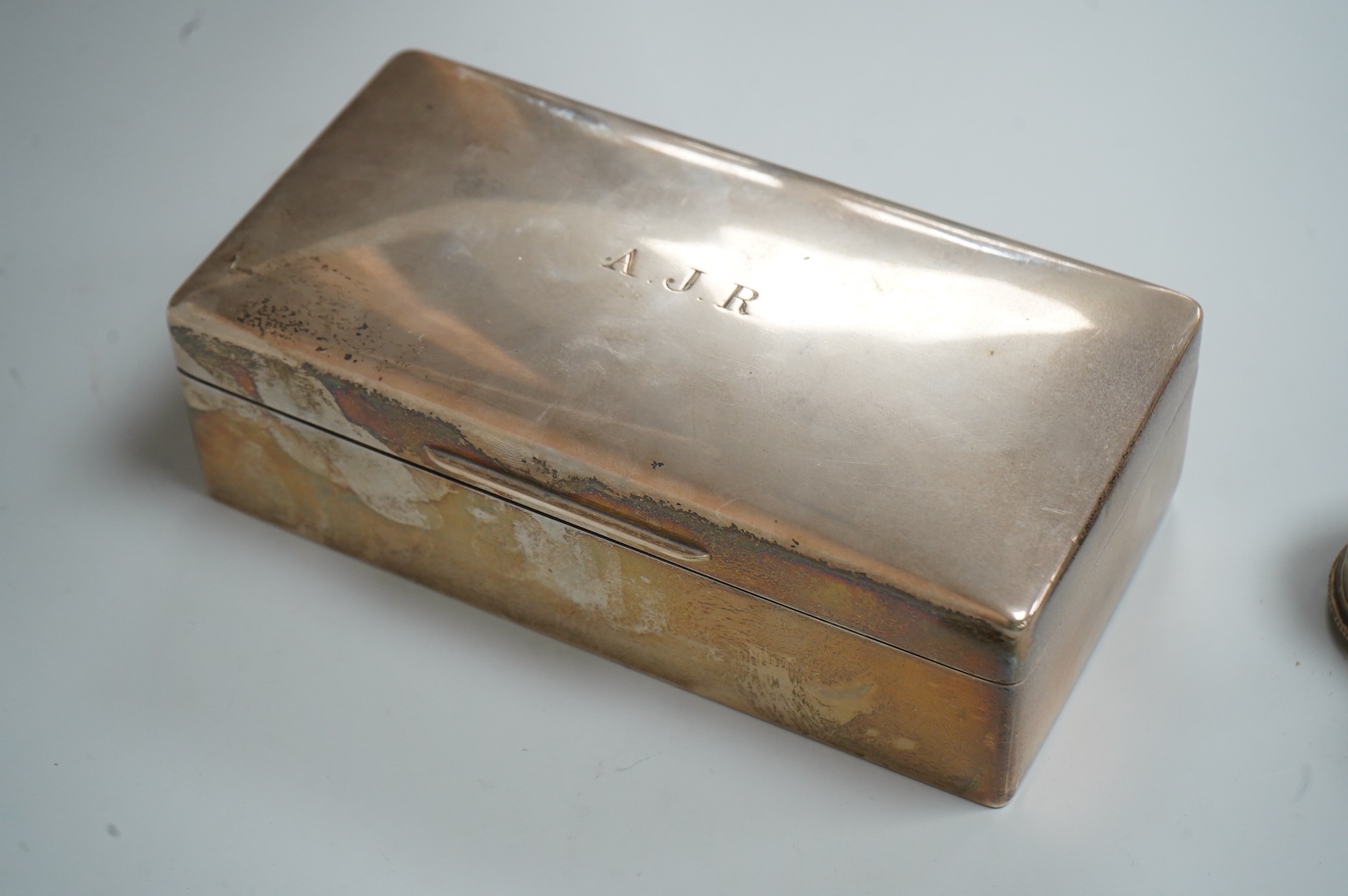 A George VI silver mounted rectangular cigarette box, Atkin Brothers, London, 1944, 17.3cm, together with a small silver dish, William Comyns & Sons Ltd, London, 1945, an Edwardian silver napkin ring and a George III sil